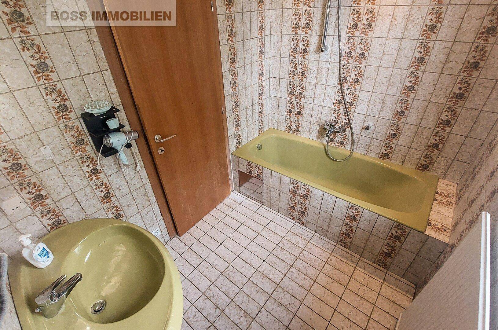 Badezimmer im Stil der 80er Jahre mit gelber Badewanne und gemusterten Fliesen.