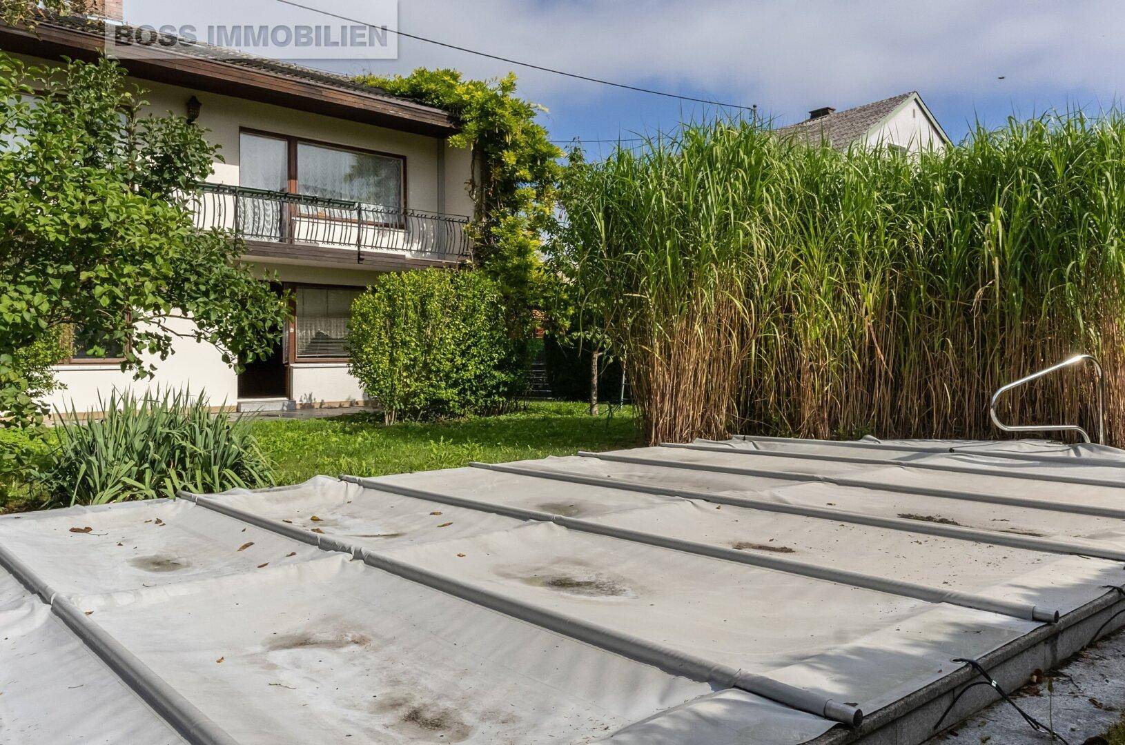Gartenansicht mit abgedecktem Pool und dem Haus im Hintergrund.