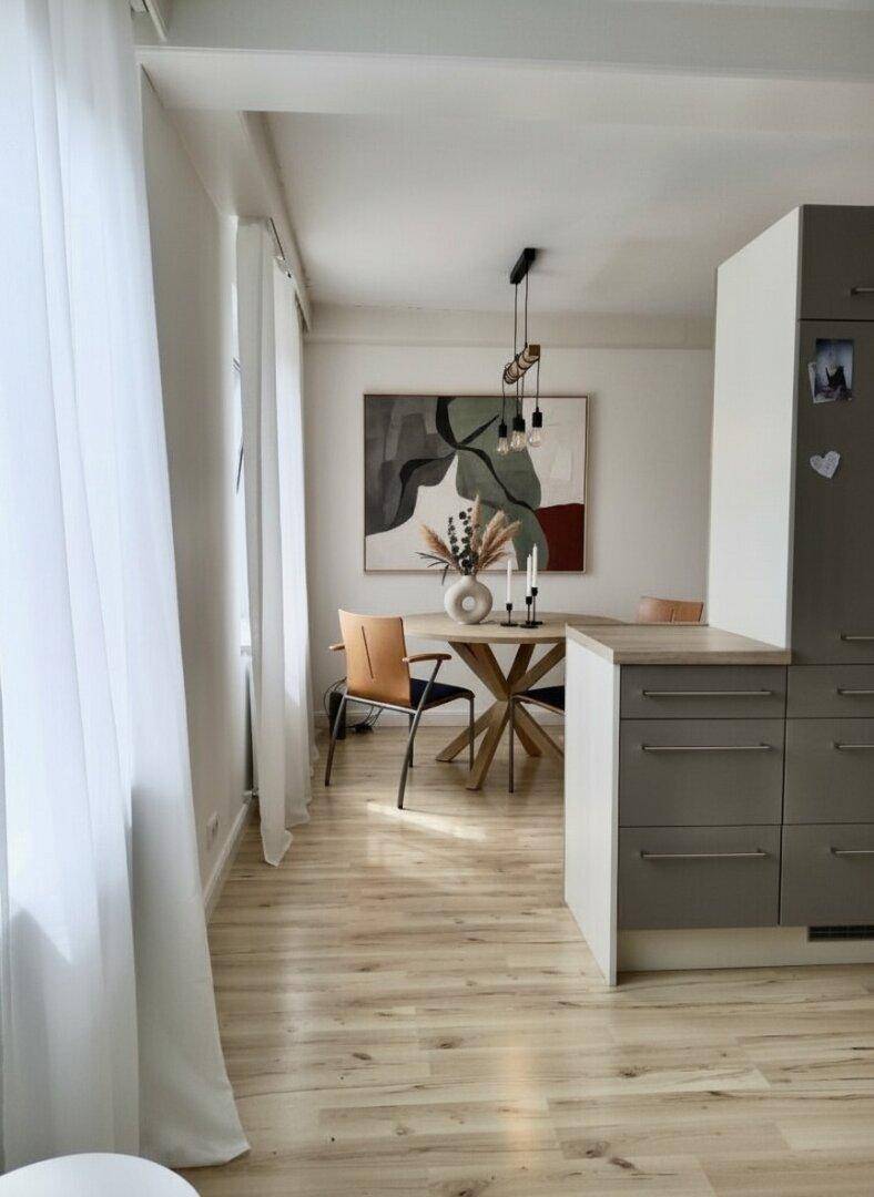 Moderner Essbereich mit Holzboden und direktem Zugang zur Küche.