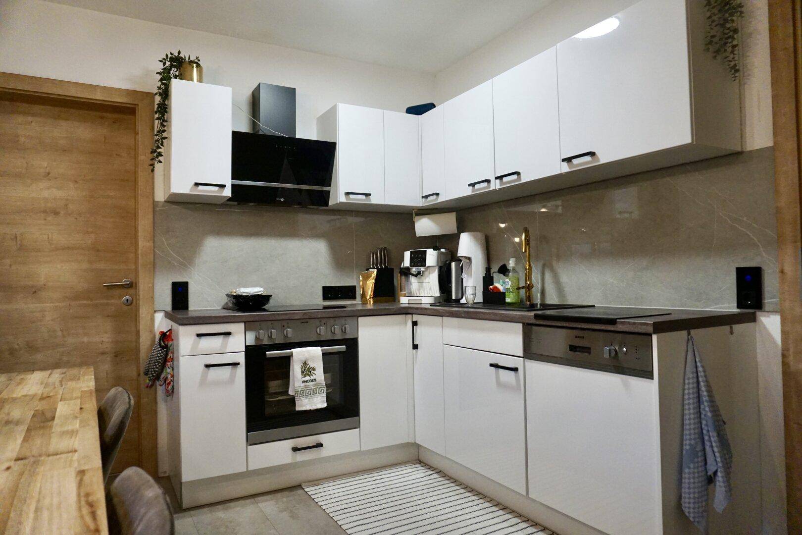 Moderne Einbauküche mit weißen Fronten, Induktionskochfeld und integriertem Backofen.