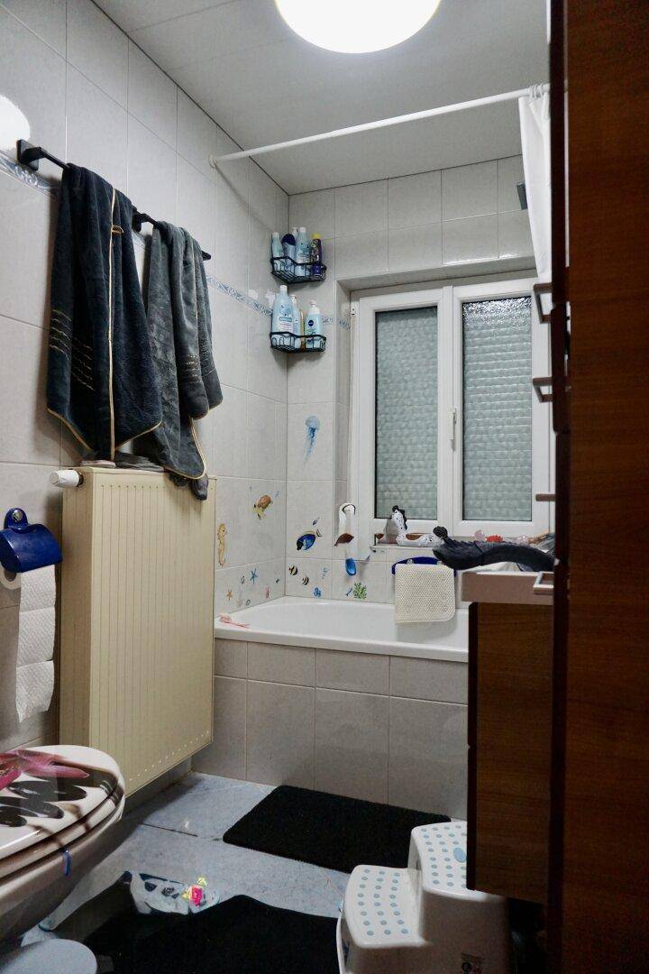 Badezimmer mit Badewanne, Fenster und Heizkörper.