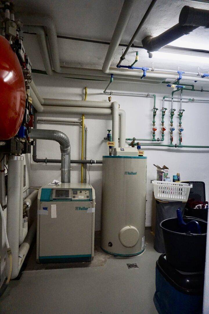 Heizungsraum im Keller mit Warmwasserspeicher und Rohrleitungen.