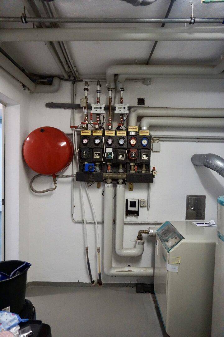 Technischer Raum im Keller mit Heizungsverteiler und Rohrinstallationen.