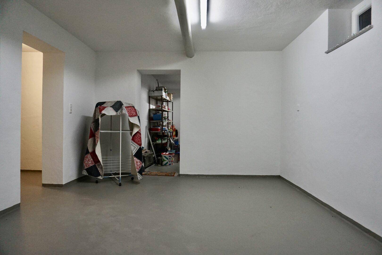 Geräumiger Kellerraum mit Betonboden und Stauraum.