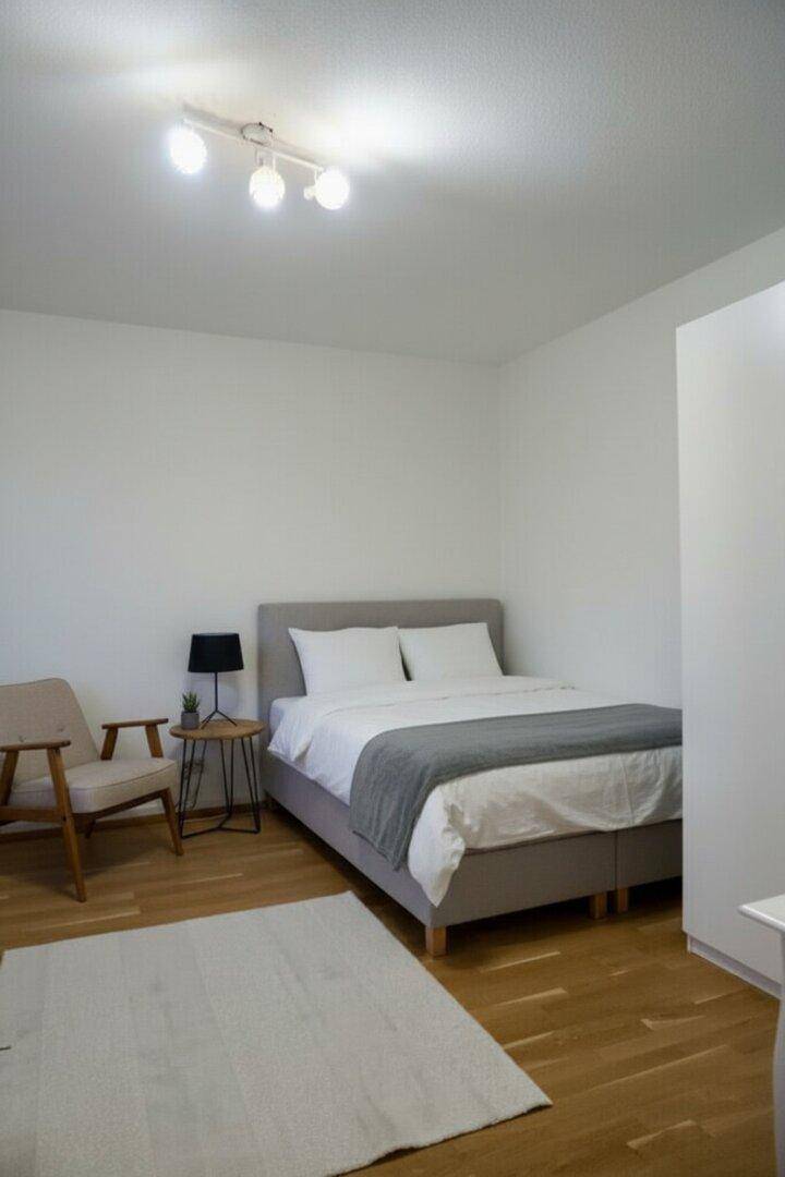 Ruhiges Schlafzimmer mit Holzboden, Doppelbett und minimalistischer Einrichtung.