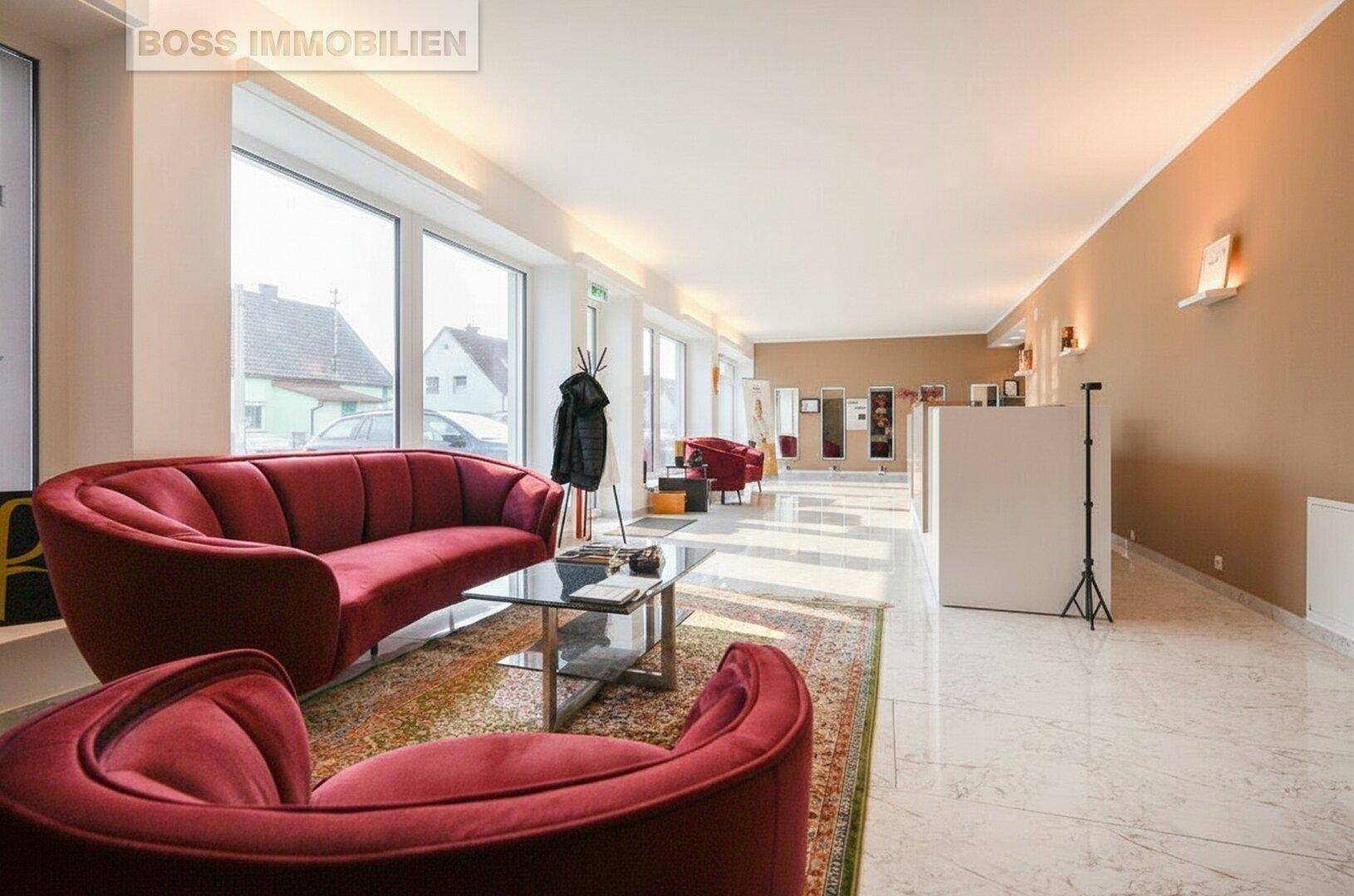 Geräumiger Empfangsbereich mit stilvollen roten Sofas, glänzendem Marmorboden und großen Fenstern zur Straße.