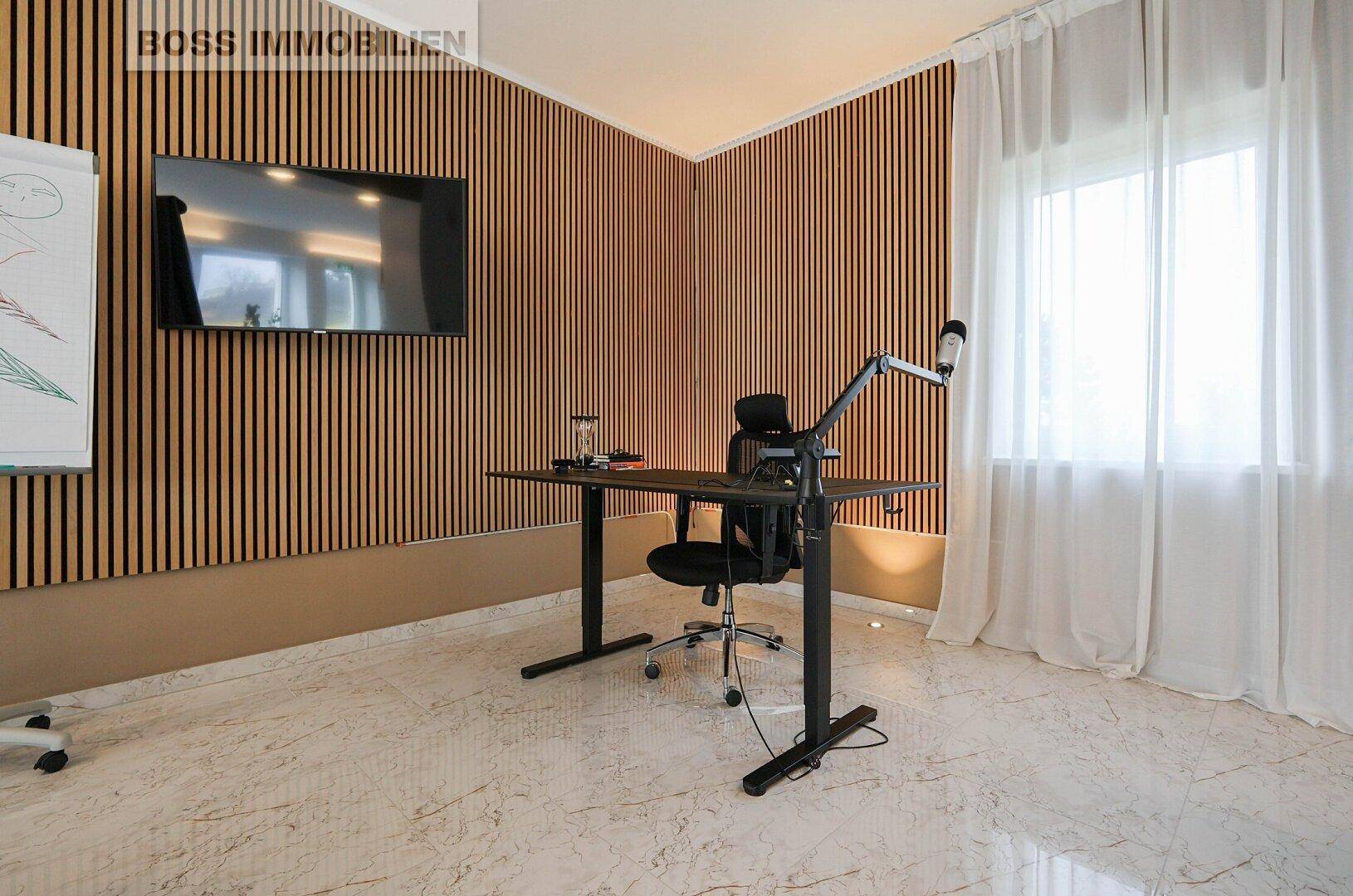 Ruhiges Büro mit Holzwandverkleidung, Schreibtisch und einem großen Fenster mit Vorhängen.