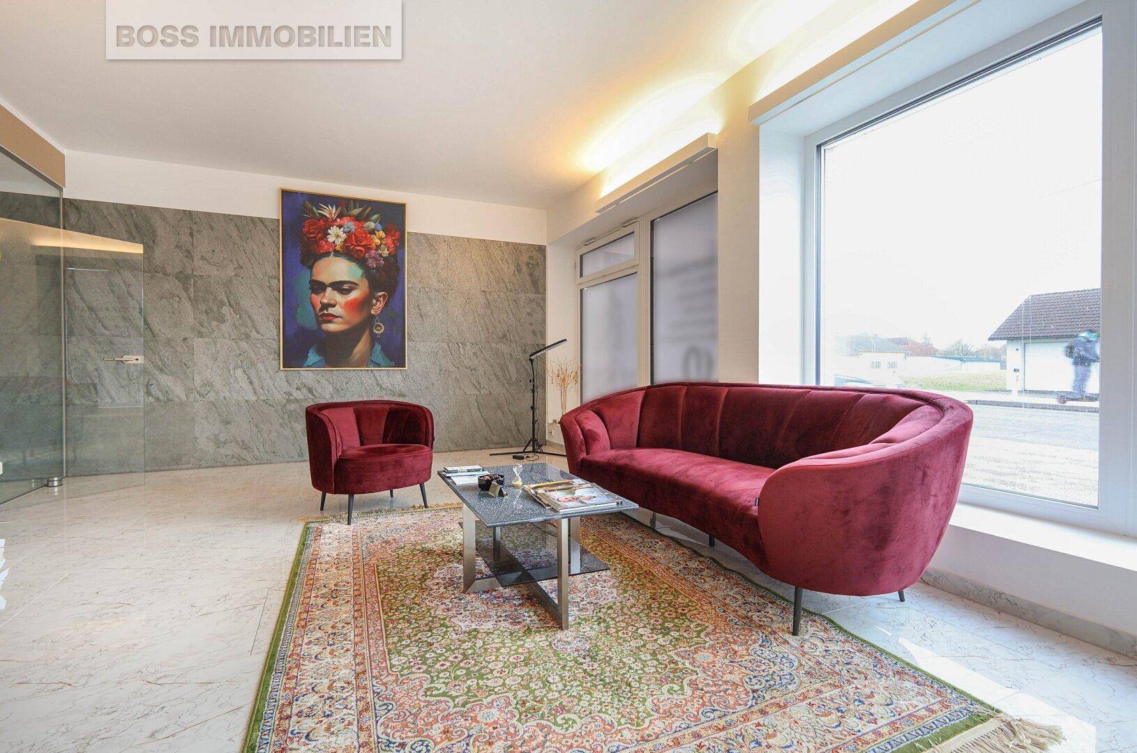 Moderner Wartebereich mit rotem Samtsofa, Marmorboden und einem auffälligen Kunstwerk an der Wand.