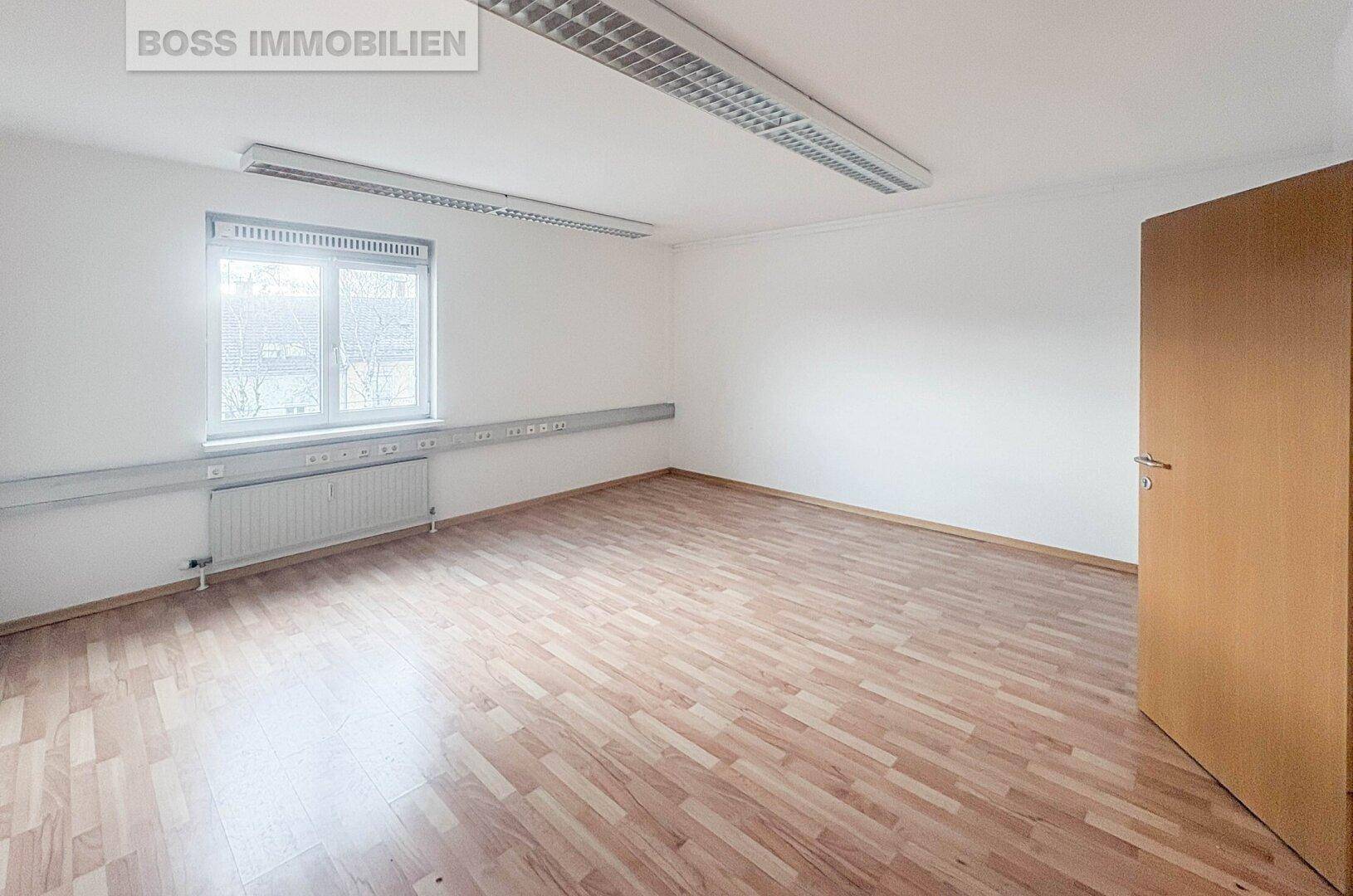 Geräumiges, unmöbliertes Büro mit hellem Holzfußboden und einem Fenster, ideal für verschiedene Nutzungen.