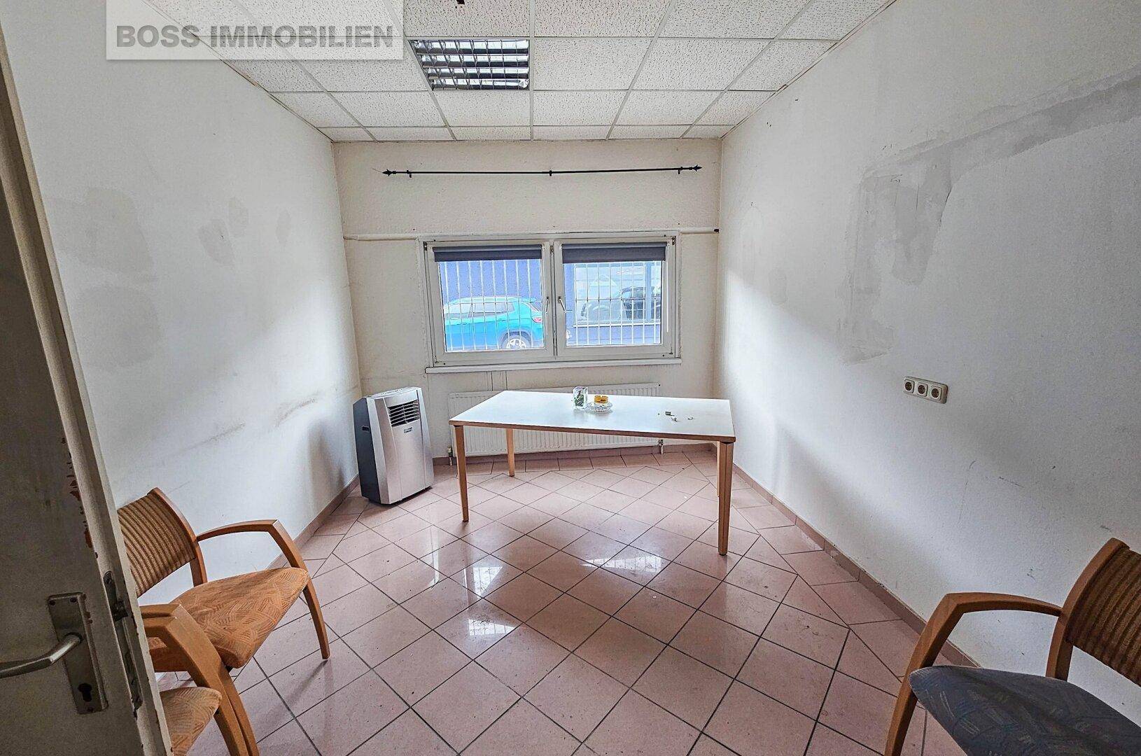Kleines Büro mit Fliesenboden, Fenster und einfacher Ausstattung.