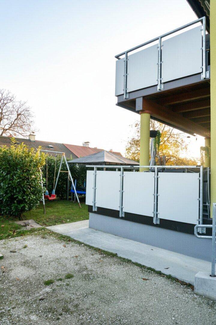 Seitlicher Gartenbereich mit Spielplatz und Zugang zum Balkon.