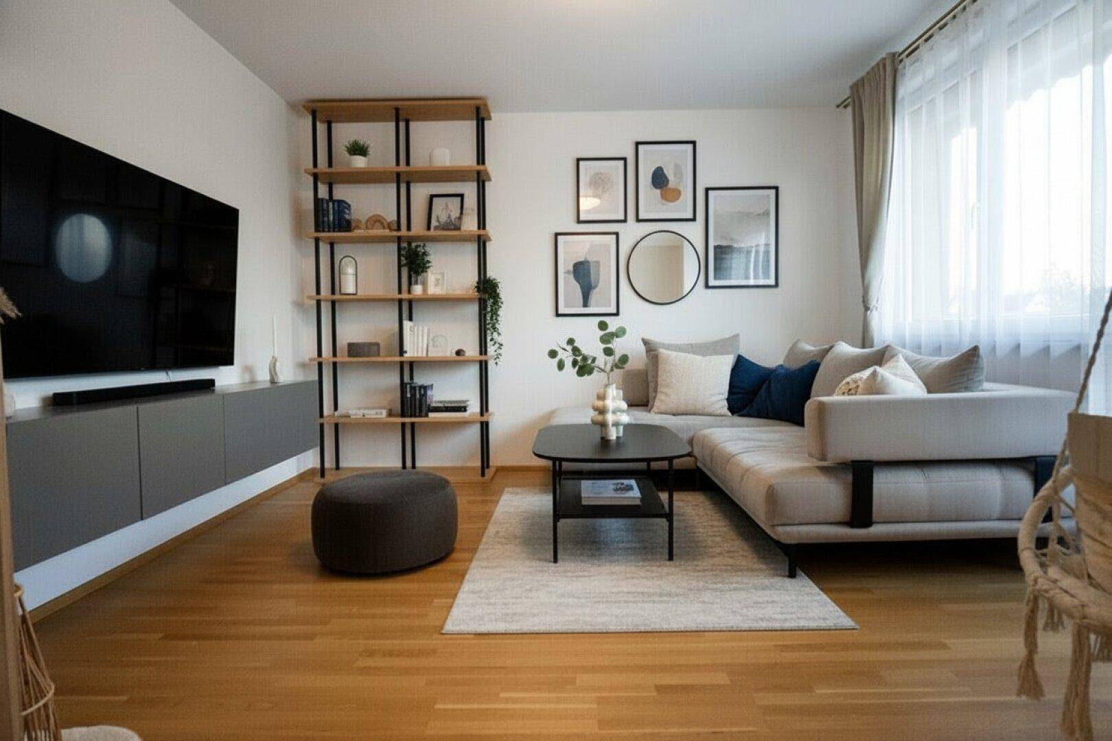 Modernes Wohnzimmer mit Holzboden, großem Sofa und Bücherregal.