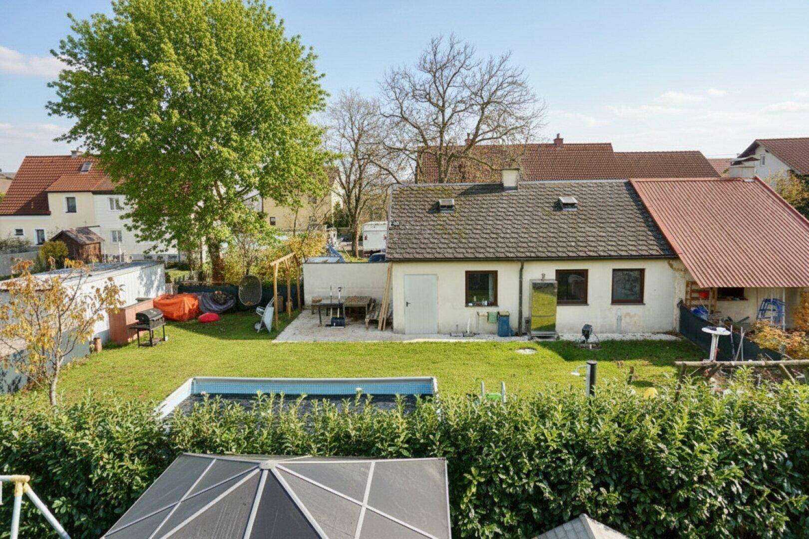 Großer Garten mit Rasenfläche, kleinem Pool und Blick auf das Haus.