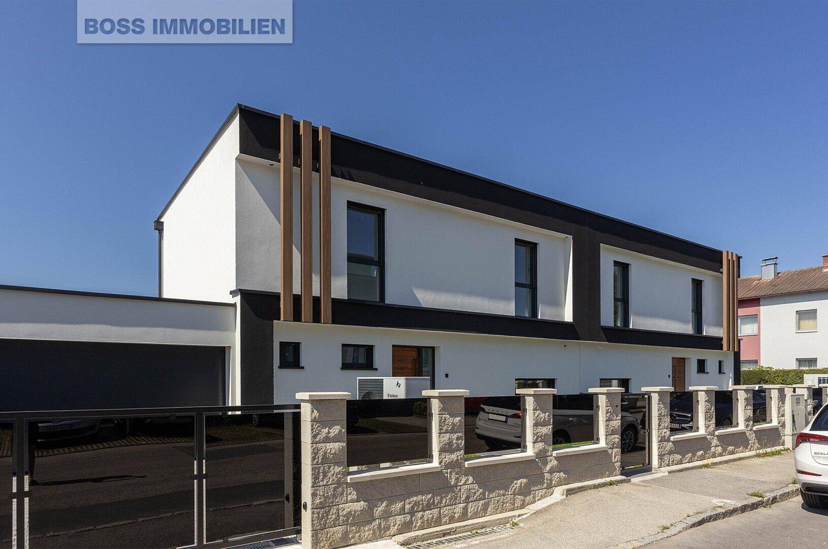 Moderne Doppelhaushälfte mit markanter schwarz-weißer Fassade und stilvollen Holzdetails.