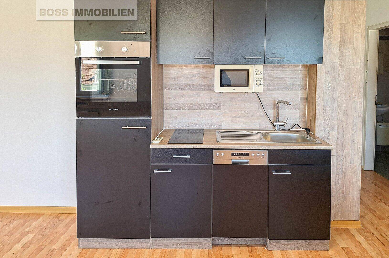 Moderne Küchenzeile mit Einbaugeräten wie Backofen, Mikrowelle, Induktionskochfeld und Geschirrspüler.