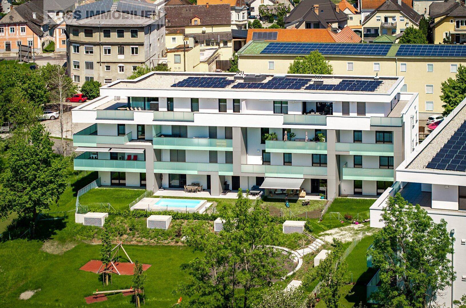 Moderne Wohngebäude mit Balkonen, Solaranlagen auf dem Dach und gemeinschaftlichen Grünflächen.