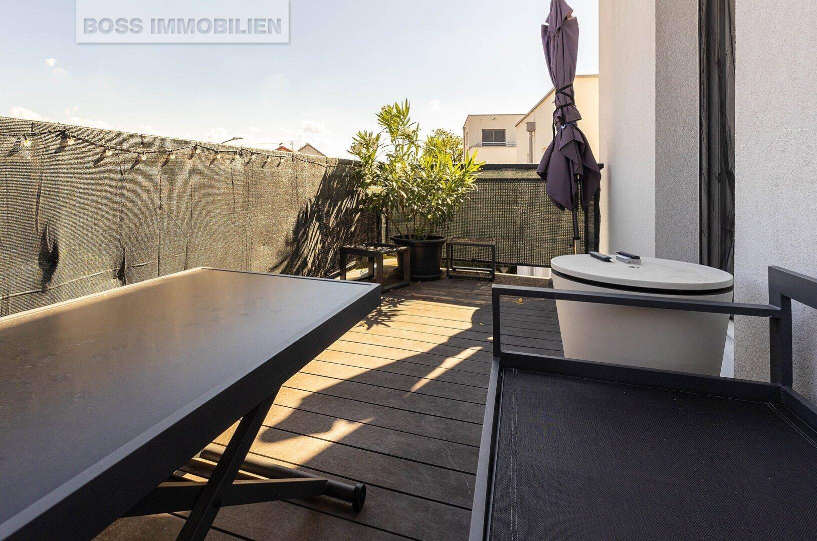 Geräumiger Balkon mit Holzboden, Pflanzen und Sonnenschirm, perfekt für sonnige Tage.