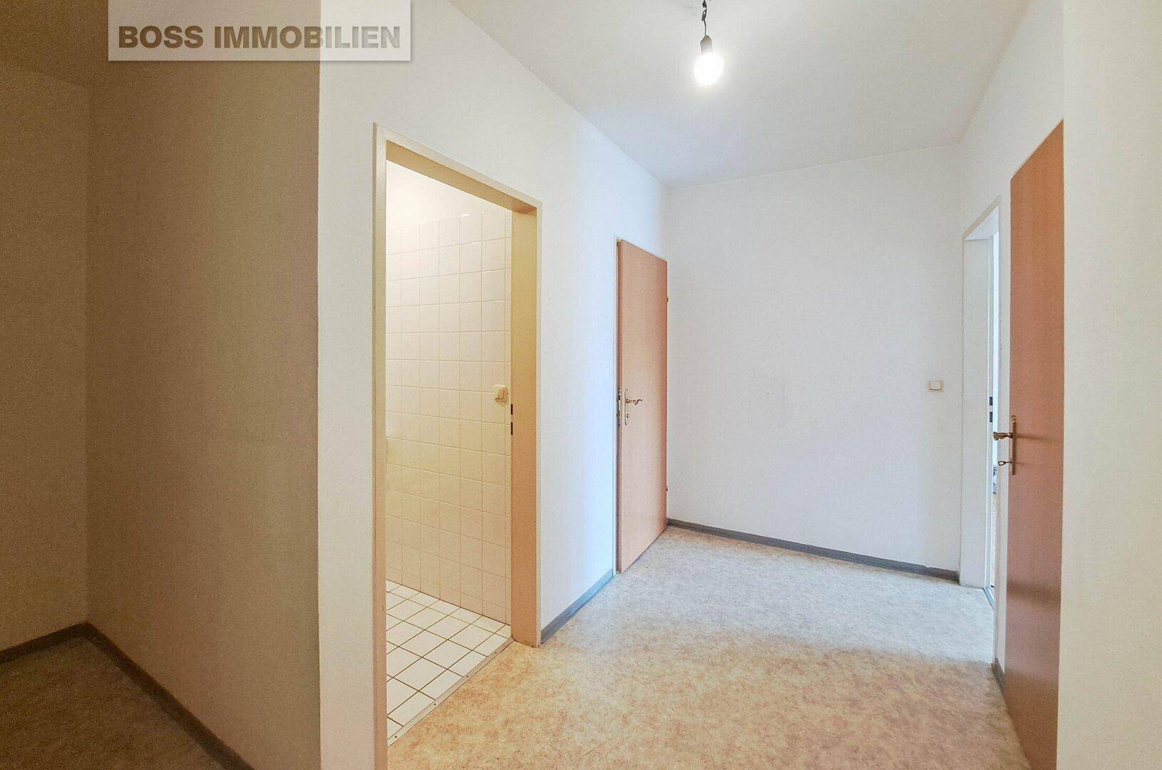 Heller Flur mit Vinylboden und Zugang zu verschiedenen Räumen, inklusive einer Duschkabine.