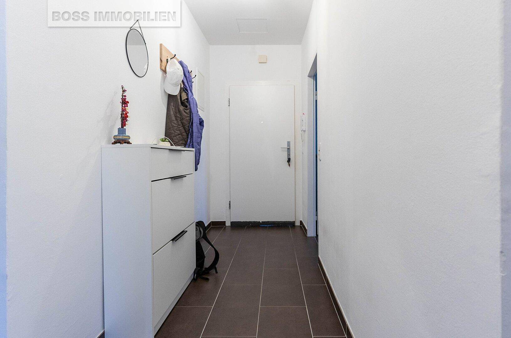 Heller Flur mit Fliesenboden, Schuhschrank und Garderobe, bietet praktischen Stauraum.