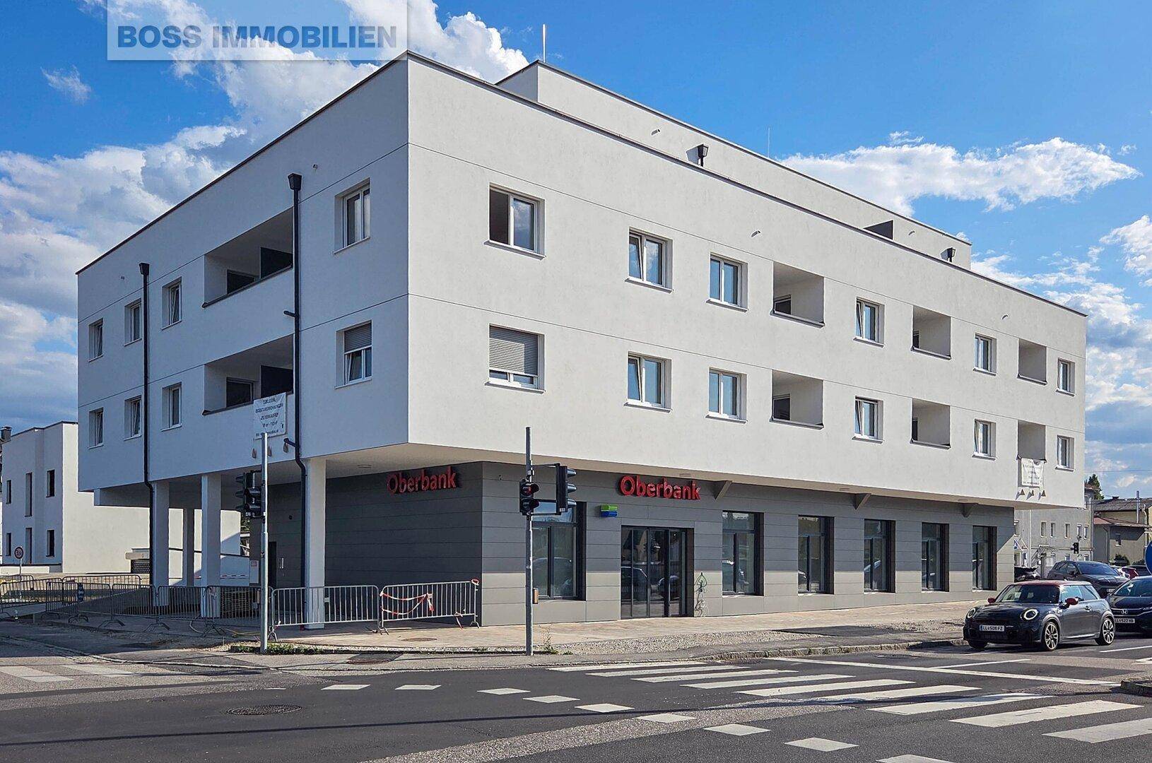 Modernes Wohn- und Geschäftsgebäude an einer Straßenecke mit Bankfiliale im Erdgeschoss.