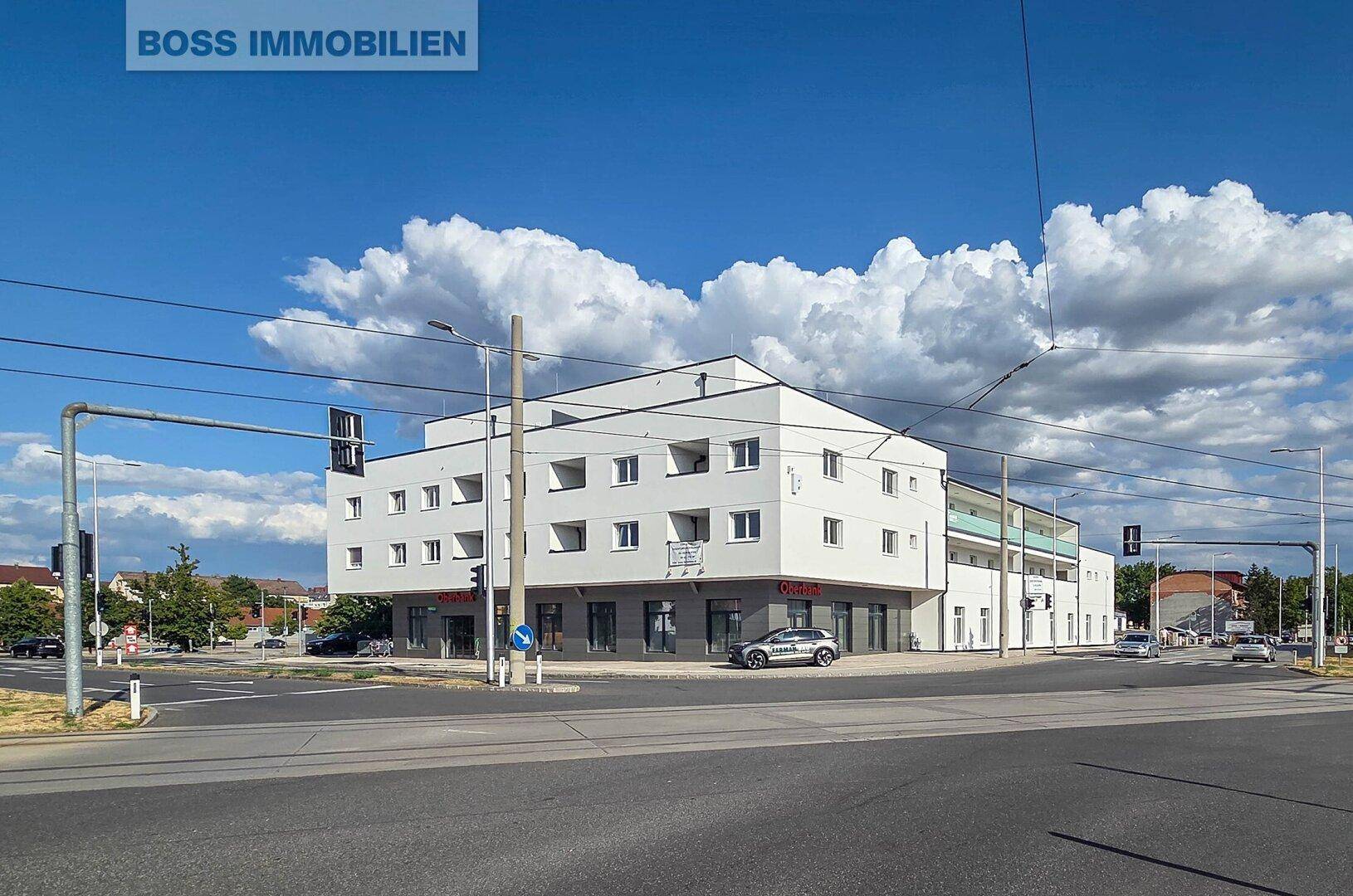 Weitläufige Ansicht des modernen Gebäudes an einer belebten Kreuzung mit klarem Himmel.