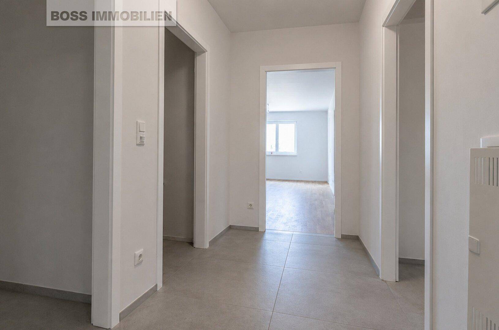 Heller Flur mit modernen Fliesen und Durchgang zu weiteren Räumen der Wohnung.