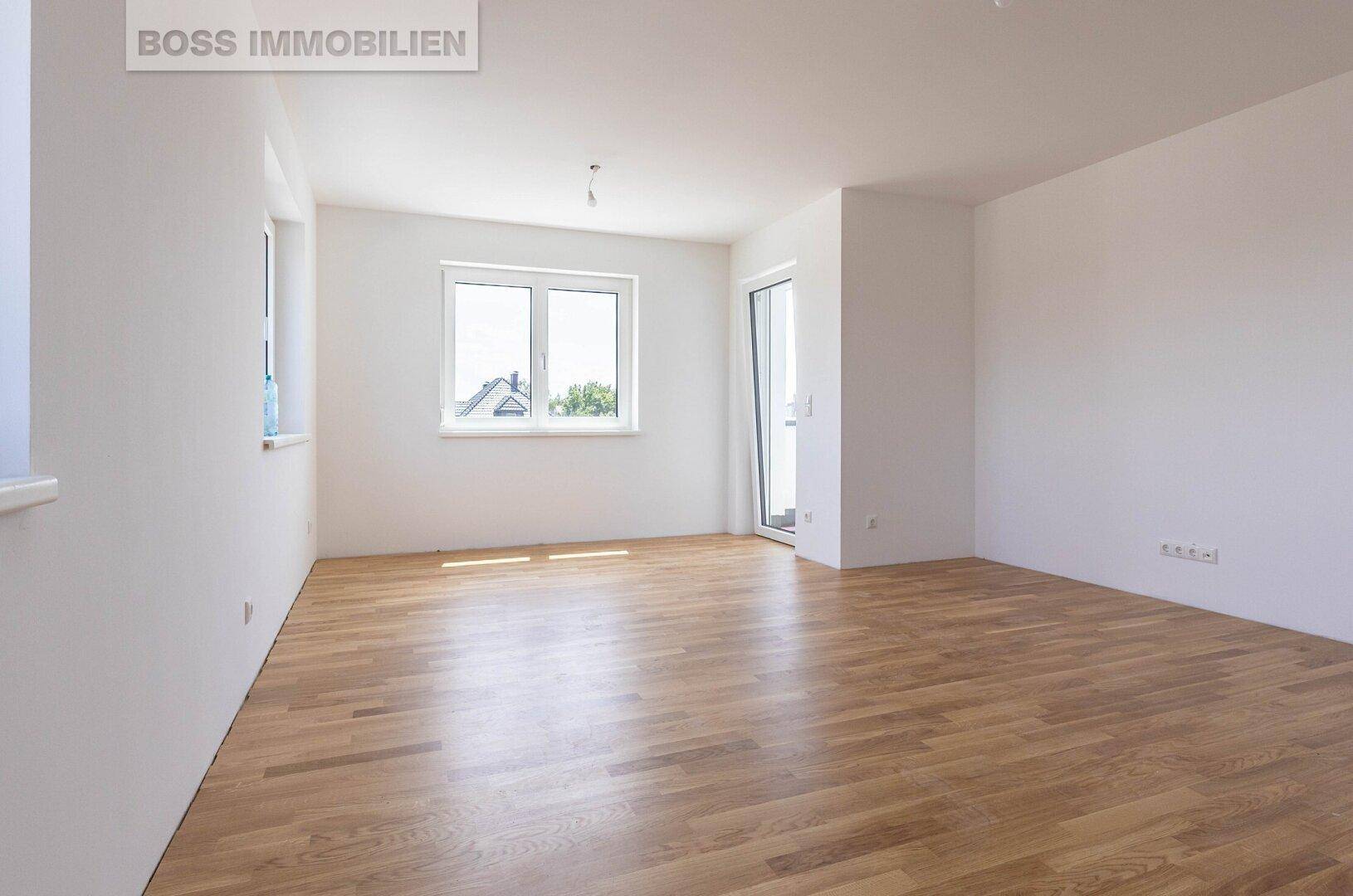 Geräumiger, heller Raum mit Holzboden und Zugang zu einem Außenbereich, frisch renoviert.