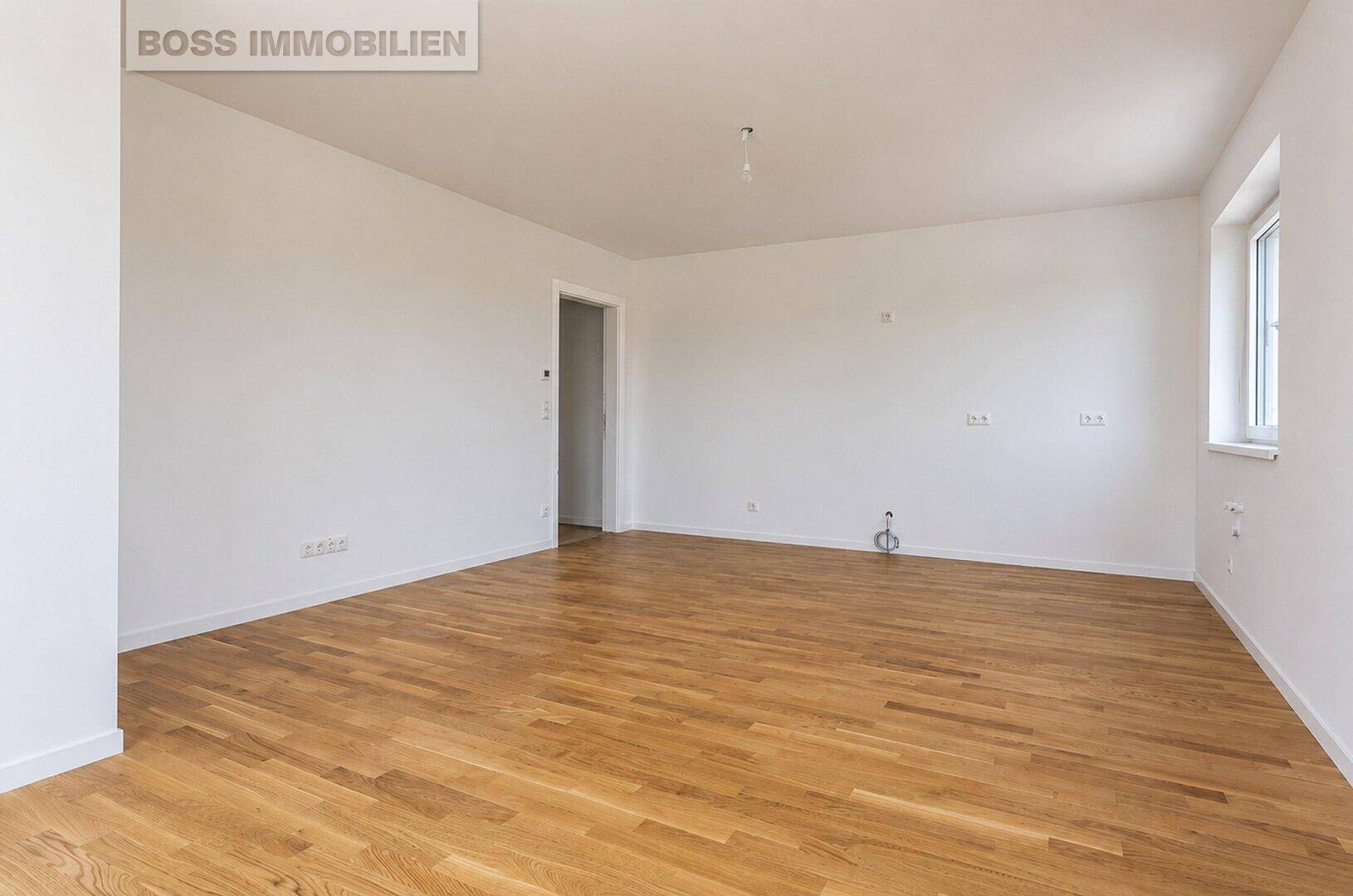 Leerer Innenraum mit hellem Holzfußboden und weiß gestrichenen Wänden, bereit zum Einzug.