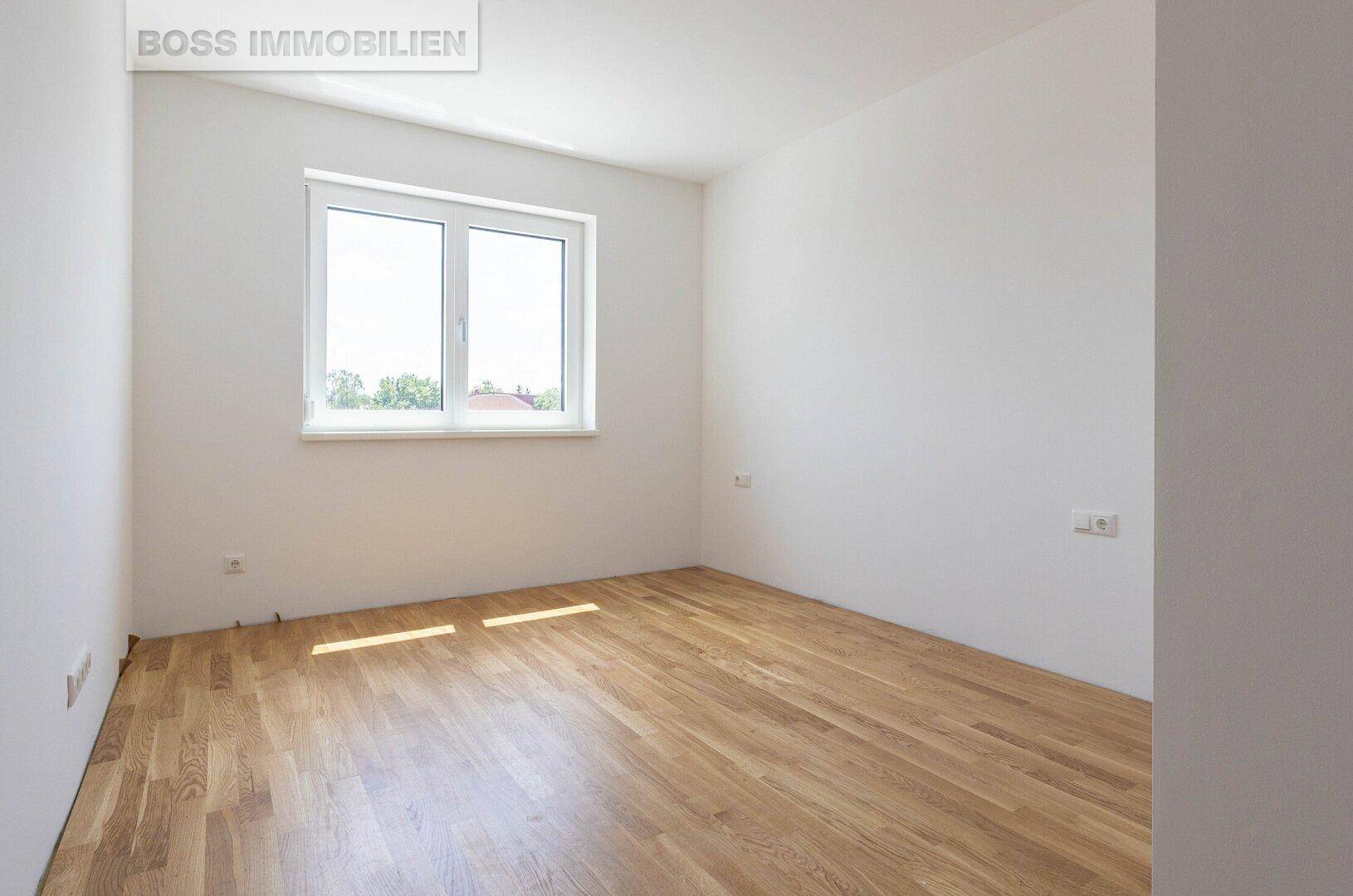 Helles Schlafzimmer mit Holzfußboden und einem großen Fenster, ideal für natürliche Belichtung.