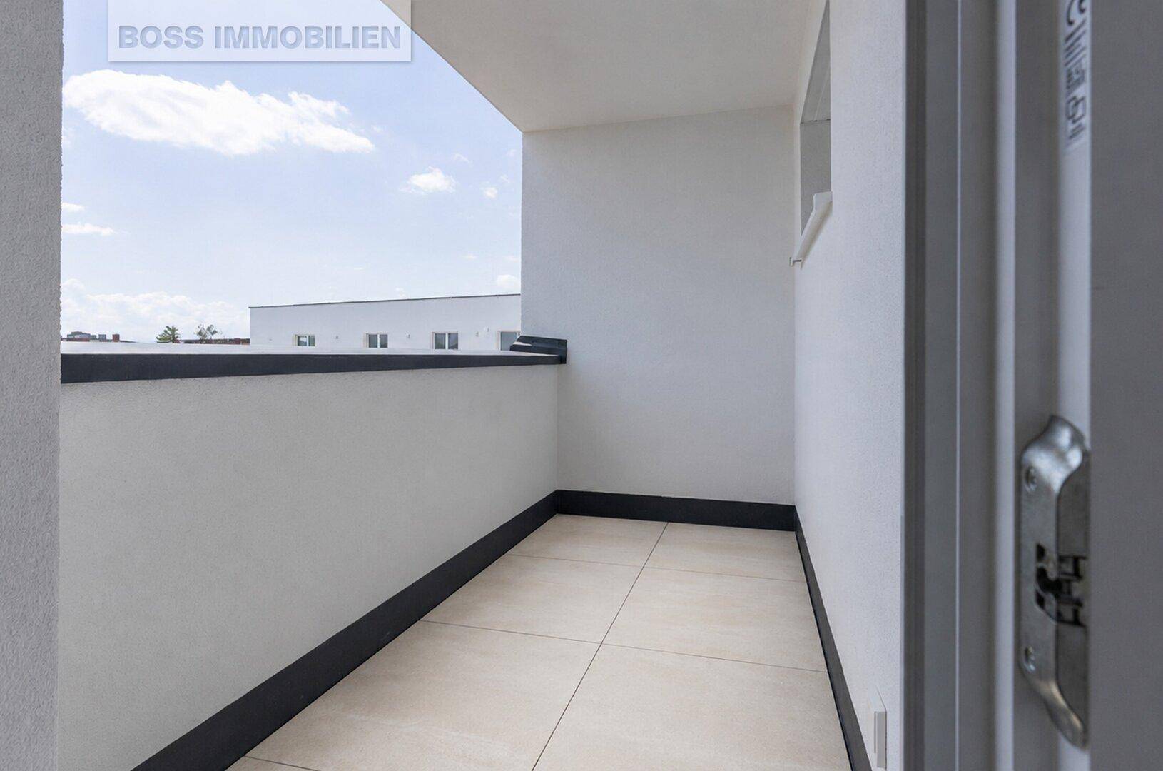 Schmaler Balkon mit Fliesenboden und weißer Brüstung, bietet einen Blick auf die Umgebung.