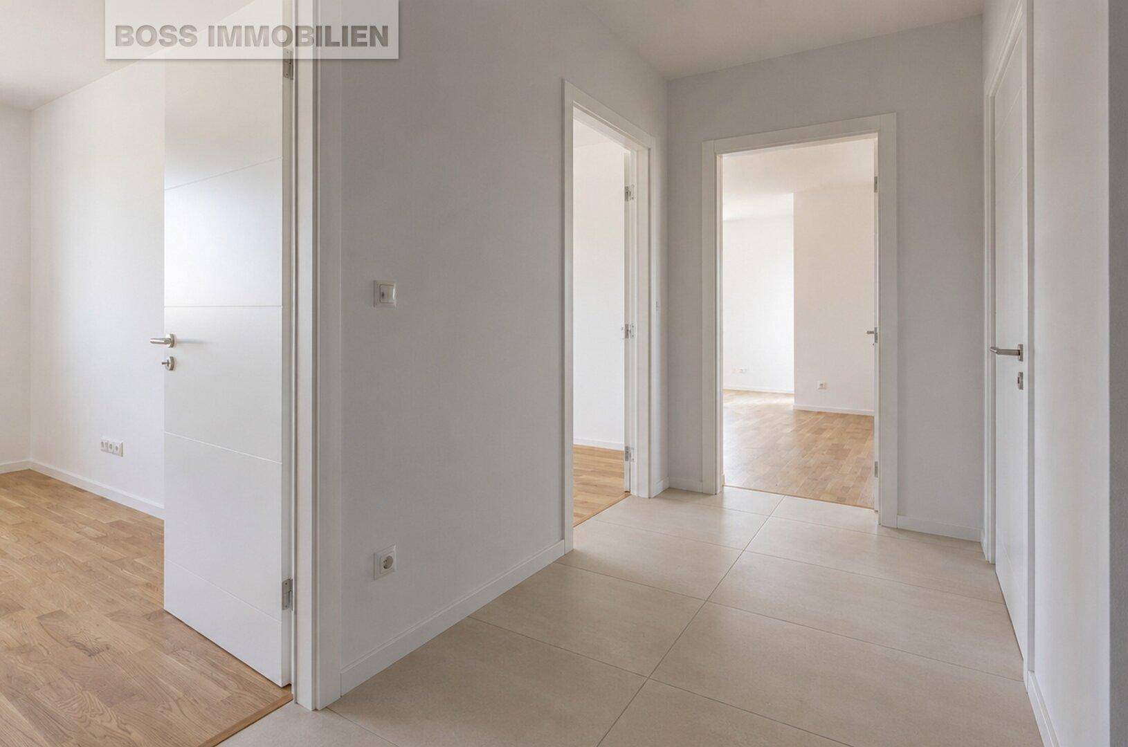 Heller Flur mit hellen Fliesen und mehreren weißen Türen, die zu den angrenzenden Räumen führen.