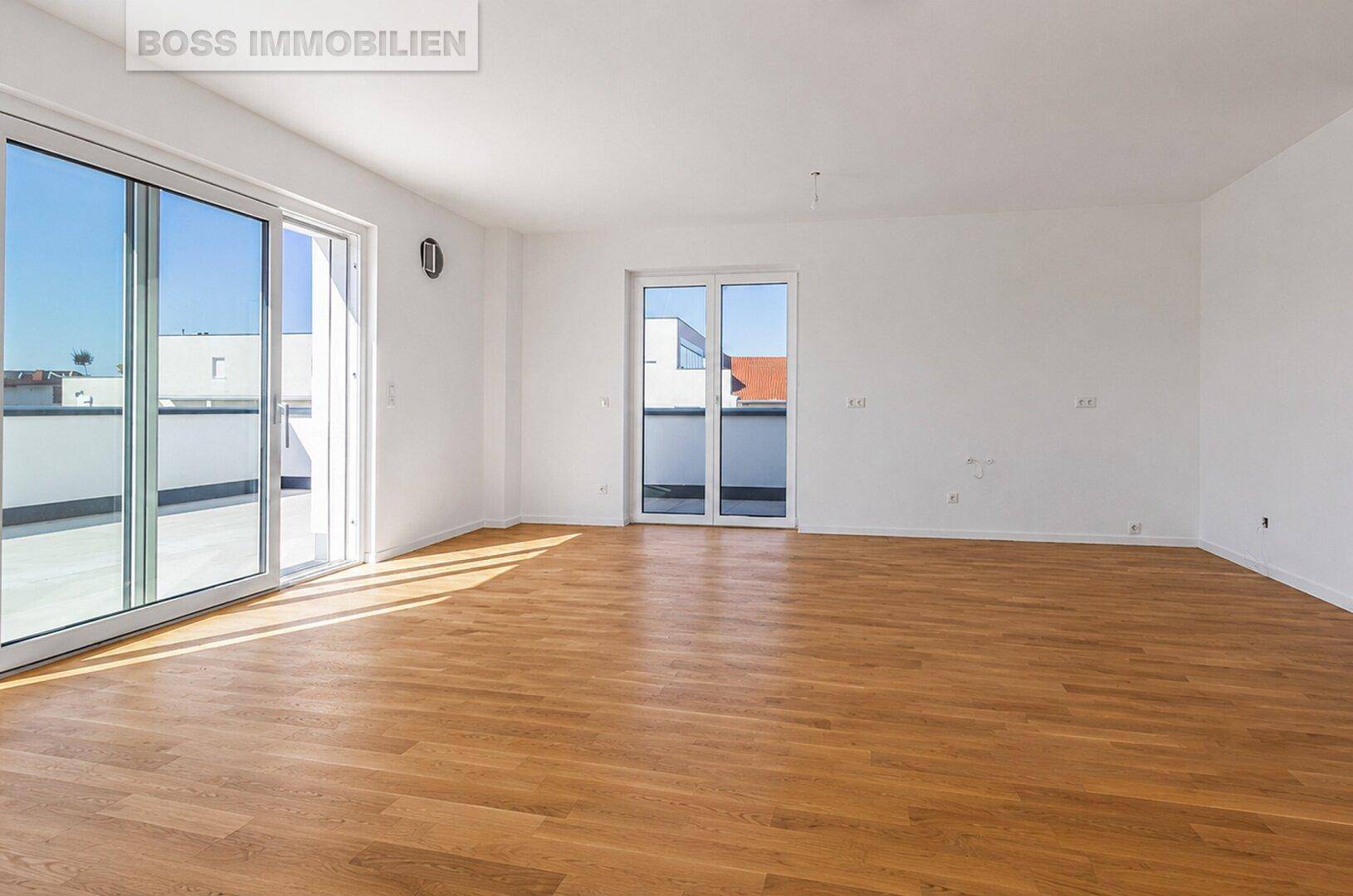 Geräumiges, helles Wohnzimmer mit Holzboden und großen Fenstern zur Terrasse.