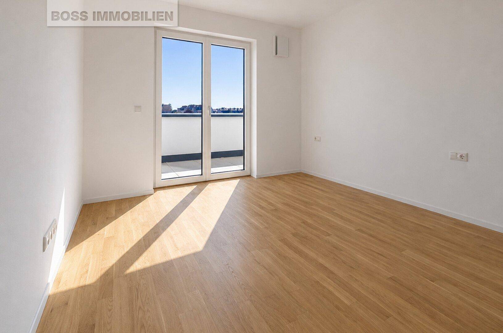 Helles Zimmer mit Parkettboden und Zugang zu einem kleinen Balkon.