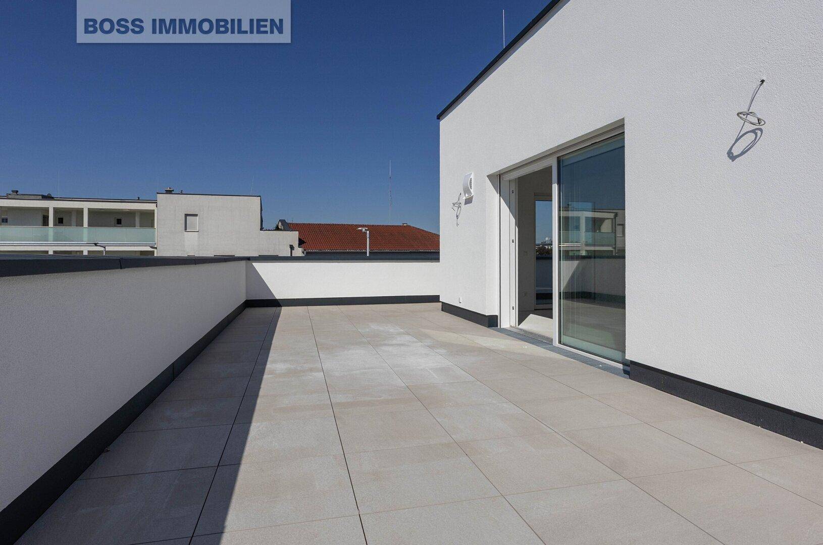 Weitläufige Dachterrasse mit hellen Fliesen und moderner Architektur.