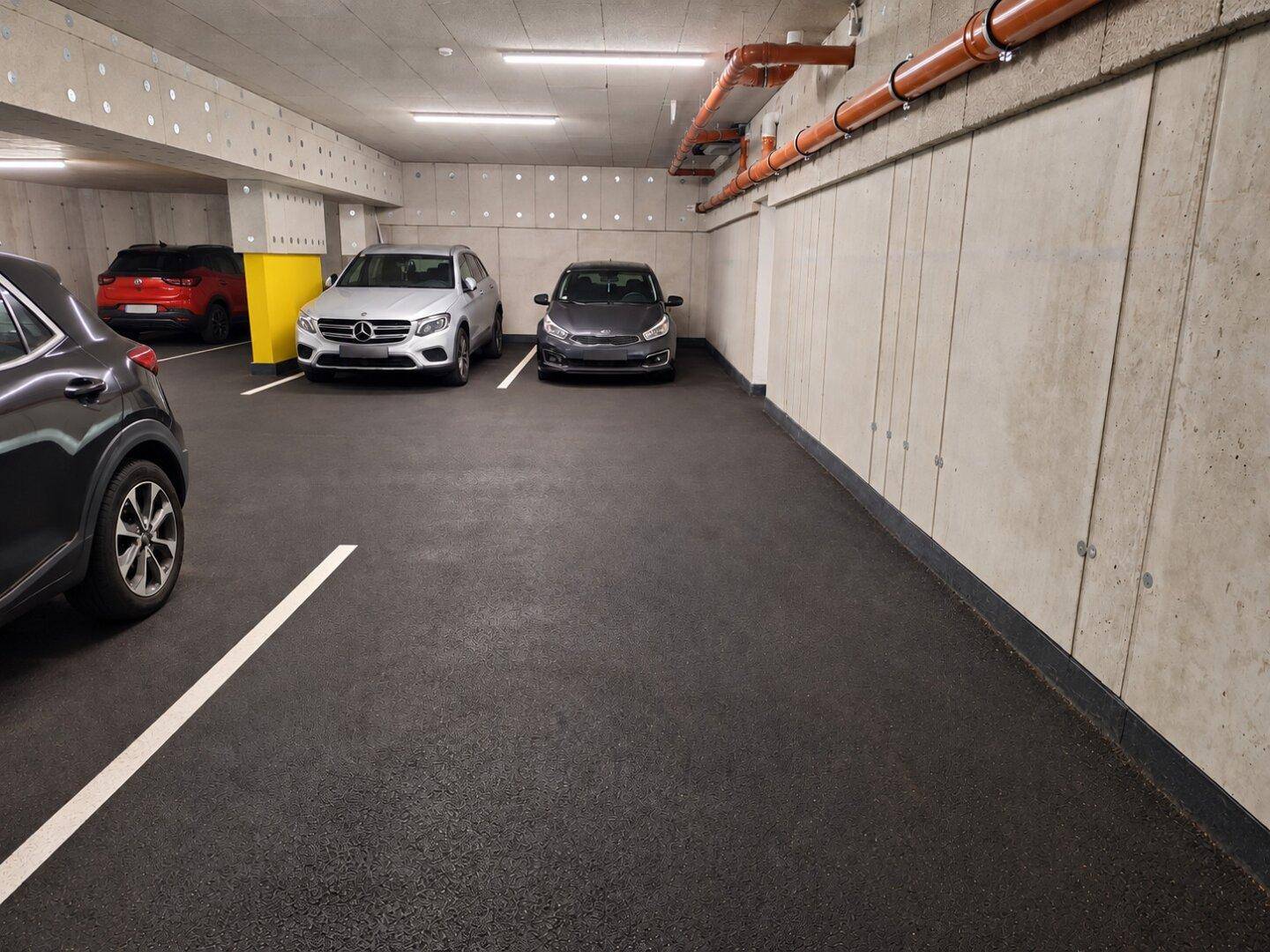 Saubere und gut beleuchtete Tiefgarage mit mehreren Stellplätzen und robusten Betonwänden.