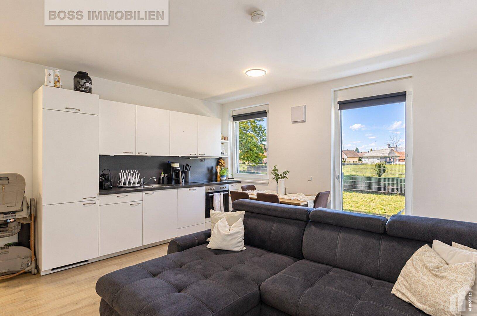 Offener Wohnbereich mit Küche, Esstisch und Blick auf den Garten durch die Fenster.