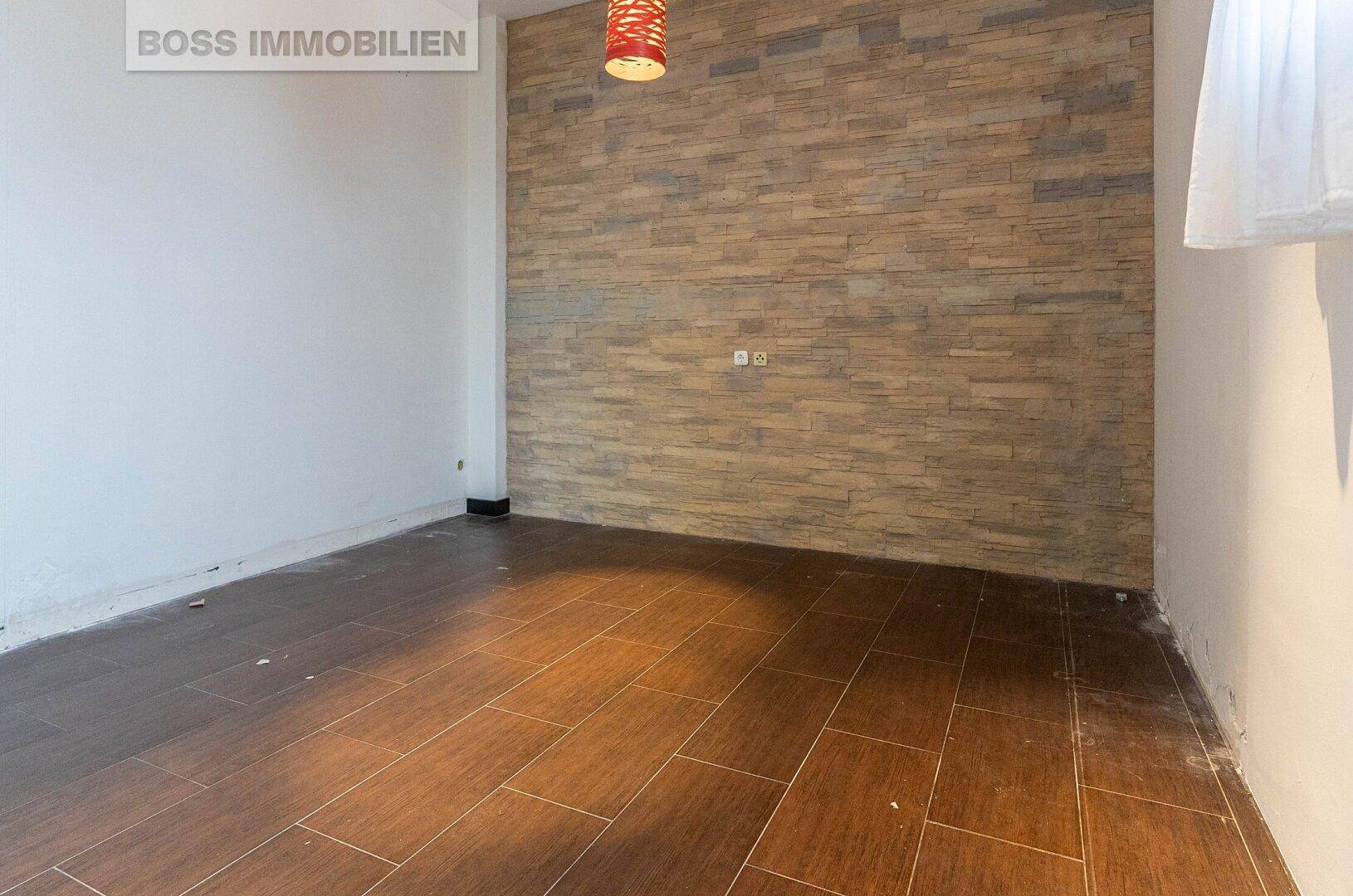 Kleiner Raum mit dunklem Fliesenboden und einer Akzentwand aus dekorativem Stein, ideal als Büro.