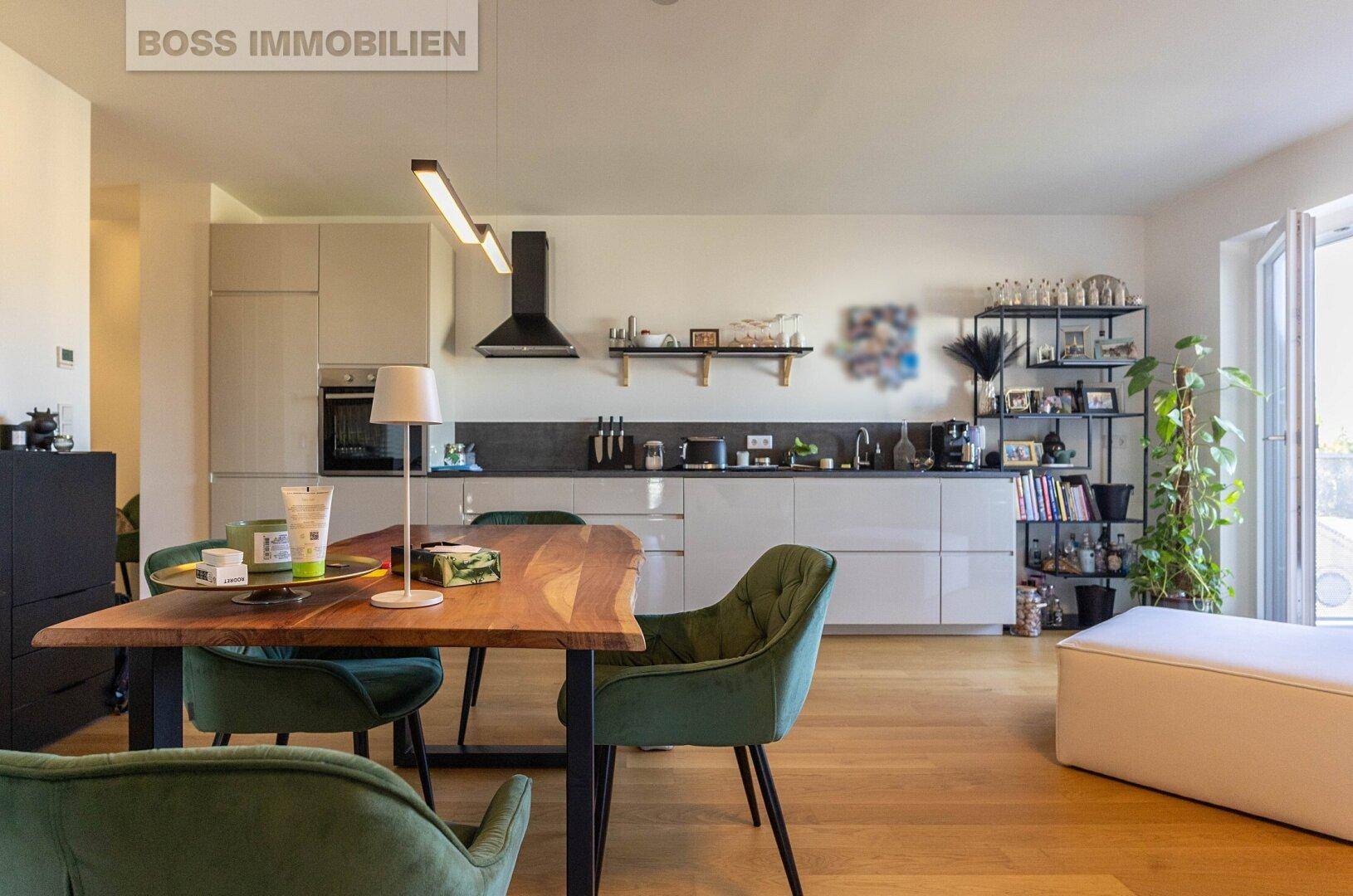 Offene, moderne Küche mit Essbereich, hellen Schränken und Holzboden.