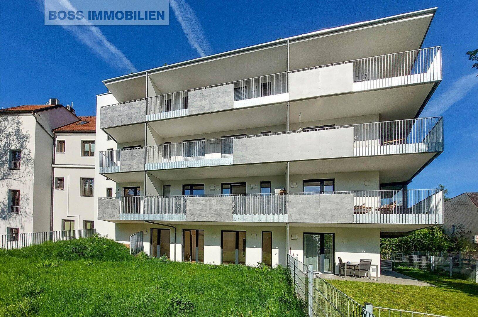 Moderne Wohnanlage mit mehreren Balkonen und gepflegter Grünfläche im Vordergrund.