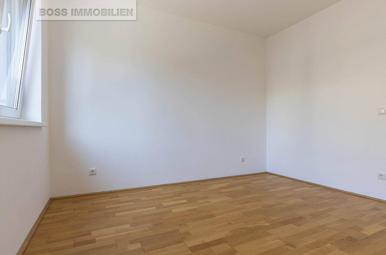 Leeres Schlafzimmer mit hellem Parkettboden und weißen Wänden, vielseitig nutzbar.