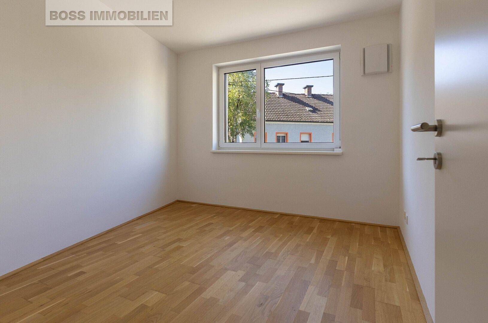Helles Zimmer mit Parkettboden und Fenster, ideal als Schlaf- oder Arbeitszimmer.