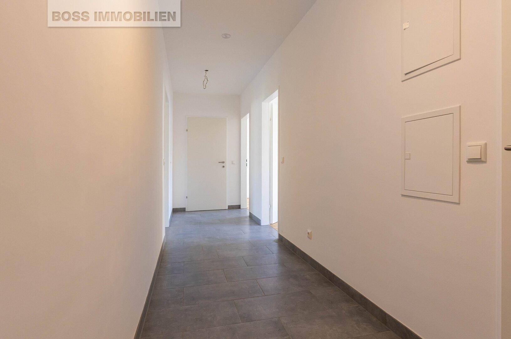 Heller Flur mit modernen grauen Fliesen und Zugang zu verschiedenen Räumen.
