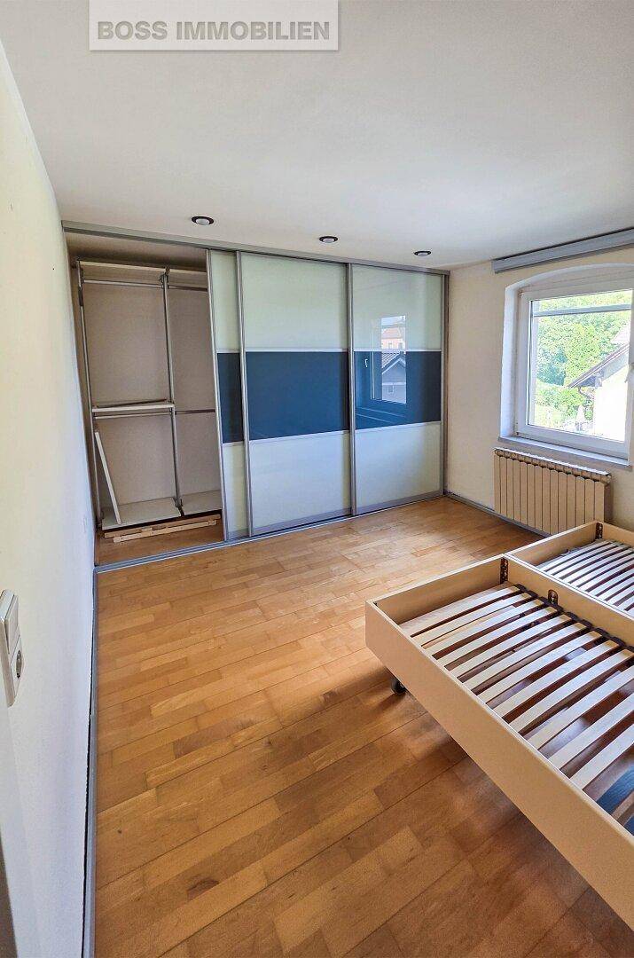Schlafzimmer mit Holzboden und einem großen Schiebetürenschrank, der viel Stauraum bietet.