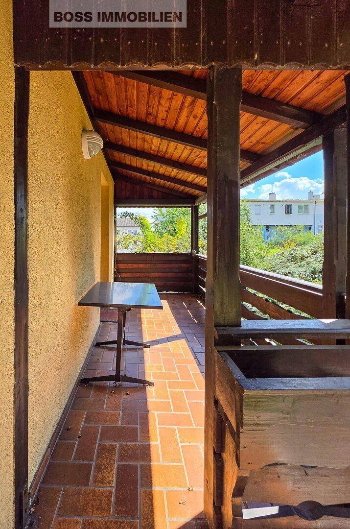 Überdachte Loggia mit Holzboden und Holzbalken, ideal für entspannte Stunden im Freien.