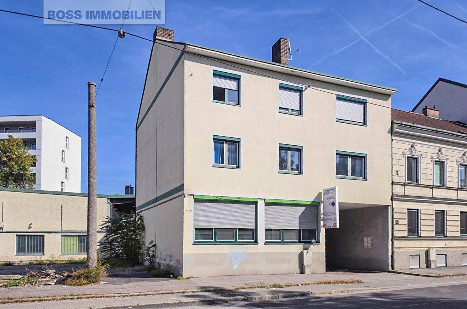 Gebäudeansicht eines Mehrfamilienhauses mit mehreren Fenstern und einem Durchgang.