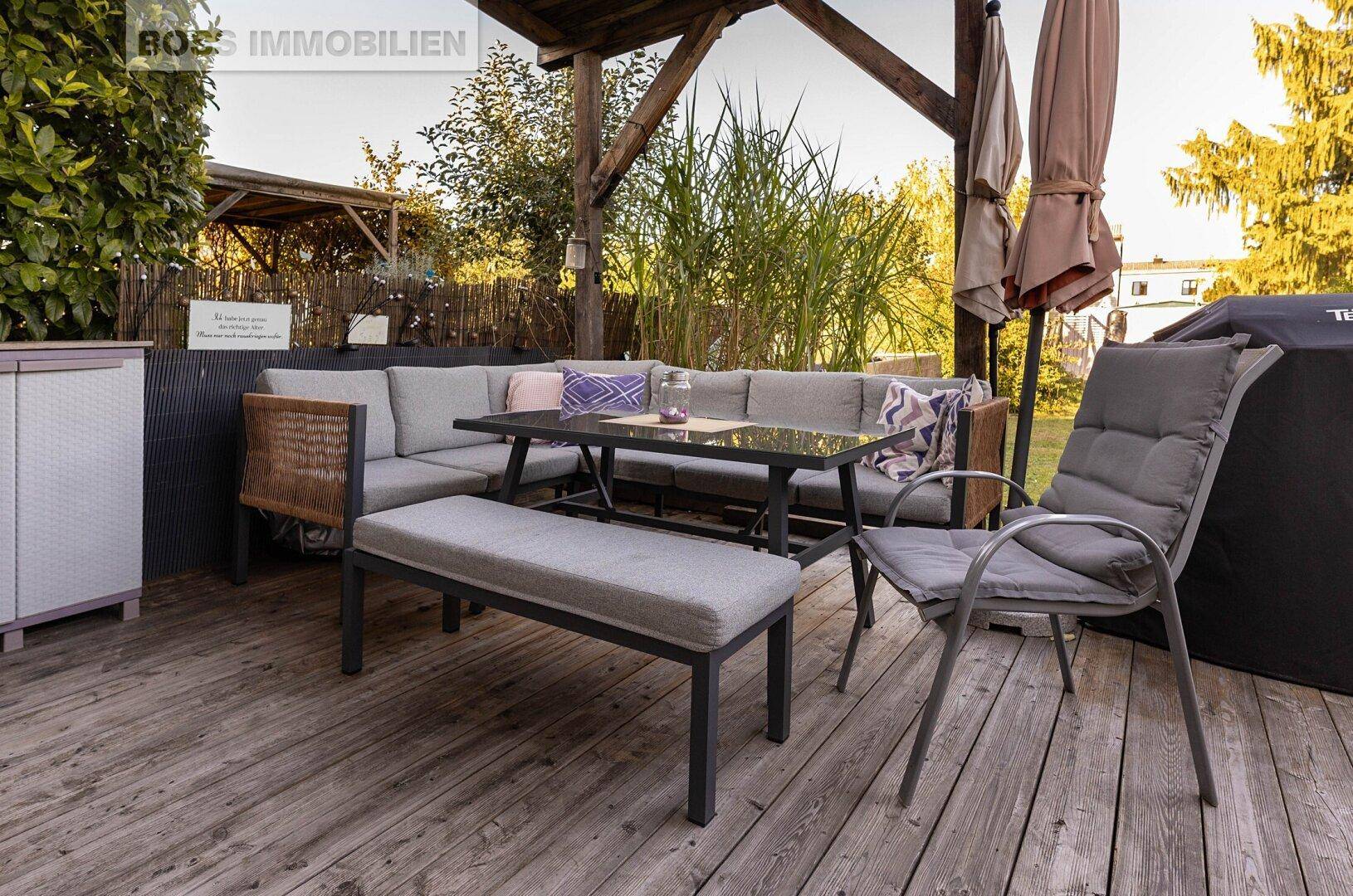 Gemütliche Holzterrasse mit Lounge-Möbeln und Sonnenschirmen im Garten.