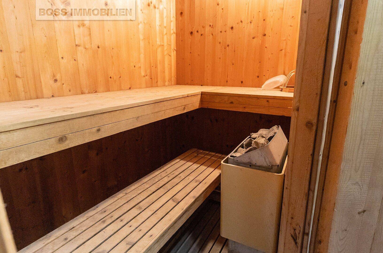 Traditionelle Holzsauna mit Sitzbänken und Saunaofen für Entspannung.