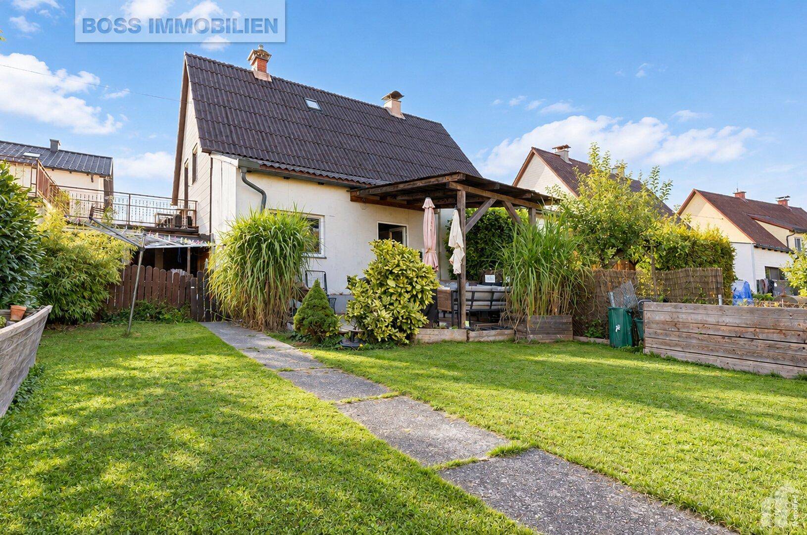 Rückansicht des Hauses mit großem Garten und überdachter Terrasse.