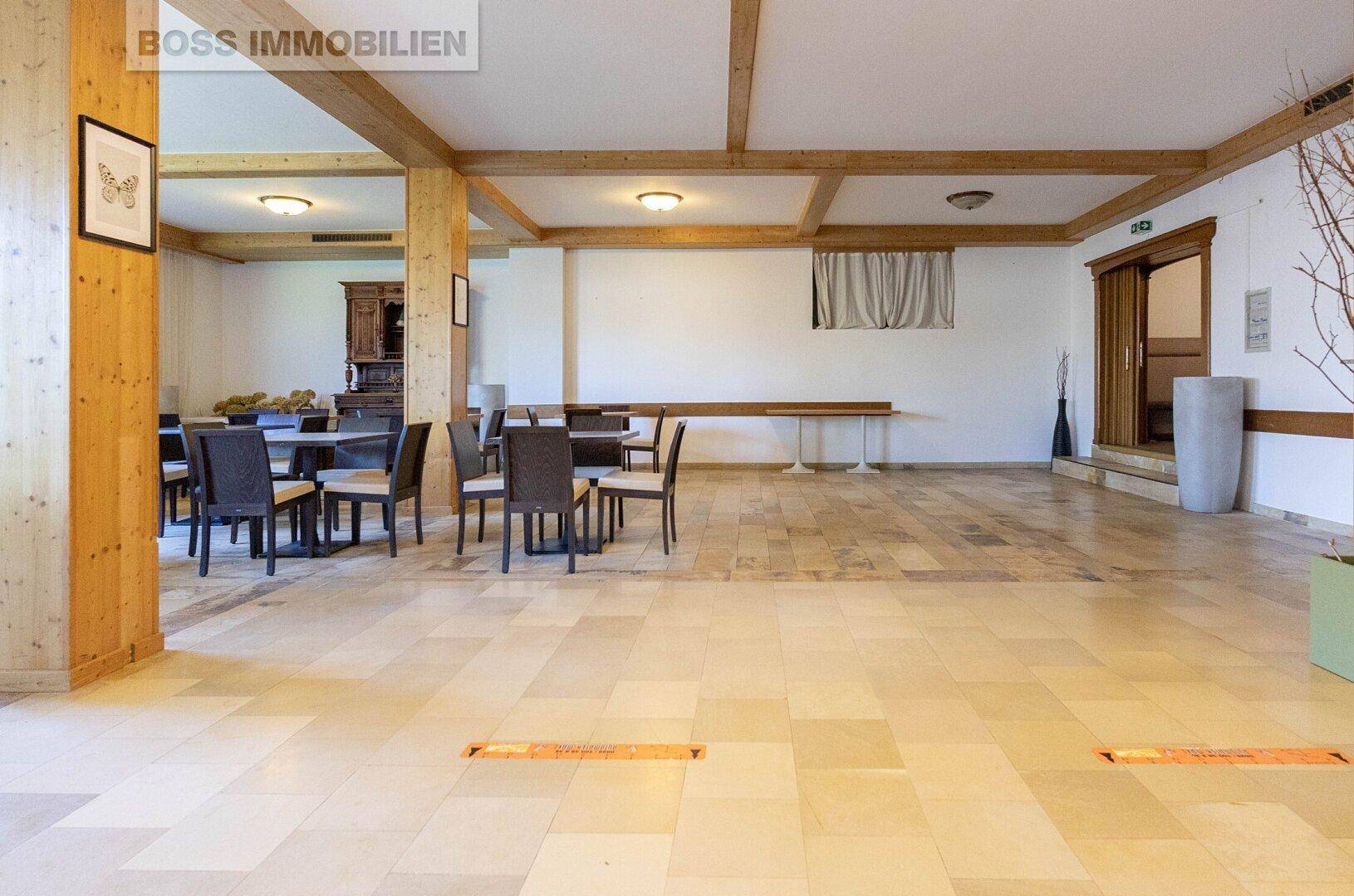 Weiterer Blick in den geräumigen Veranstaltungsraum mit Fliesenboden und Holzelementen.