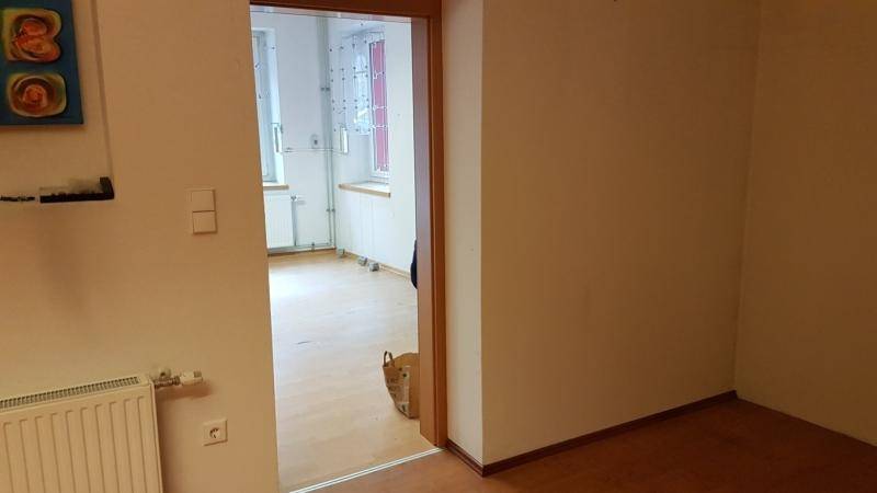 Blick durch eine offene Tür in einen weiteren Raum mit hellem Laminatboden und weißen Wänden.